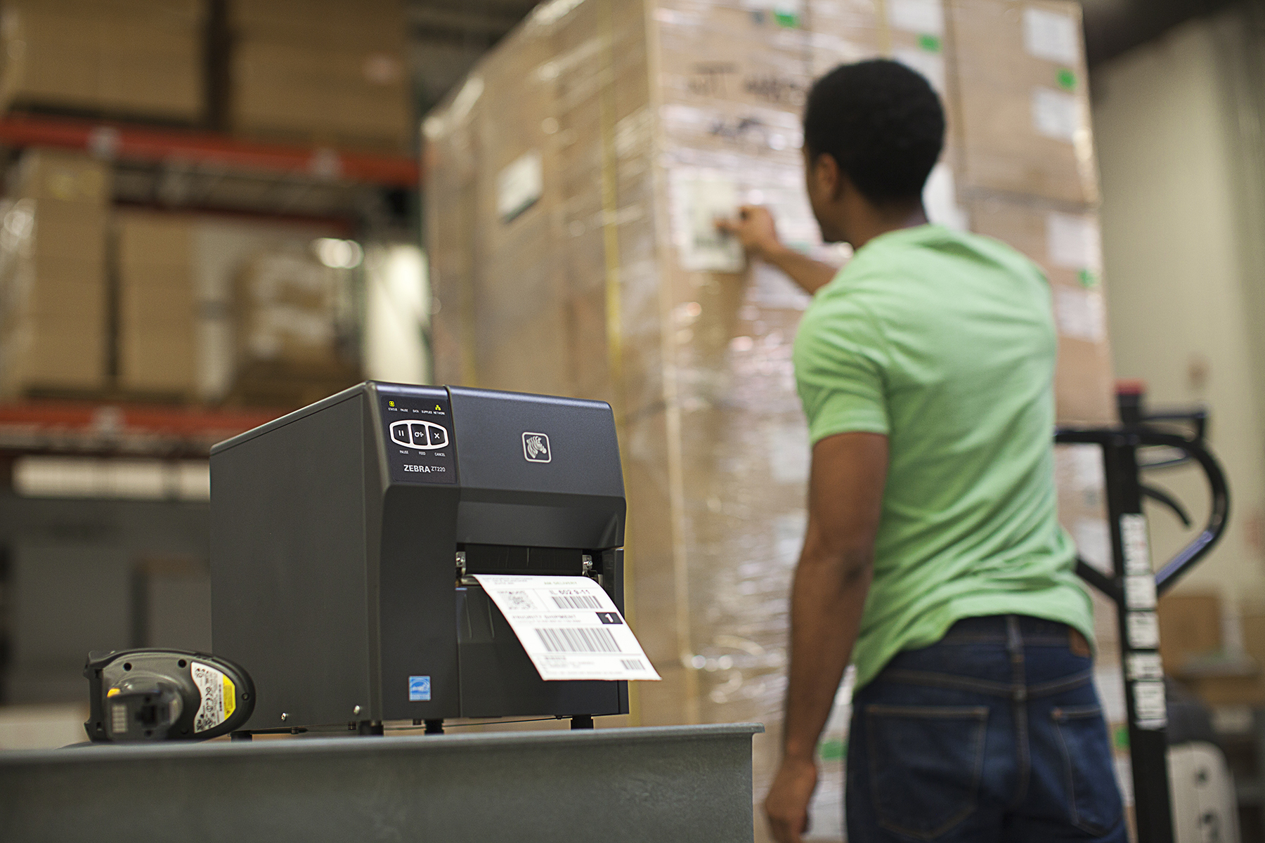 Warehouse worker printing and applying label to wrapped pallet